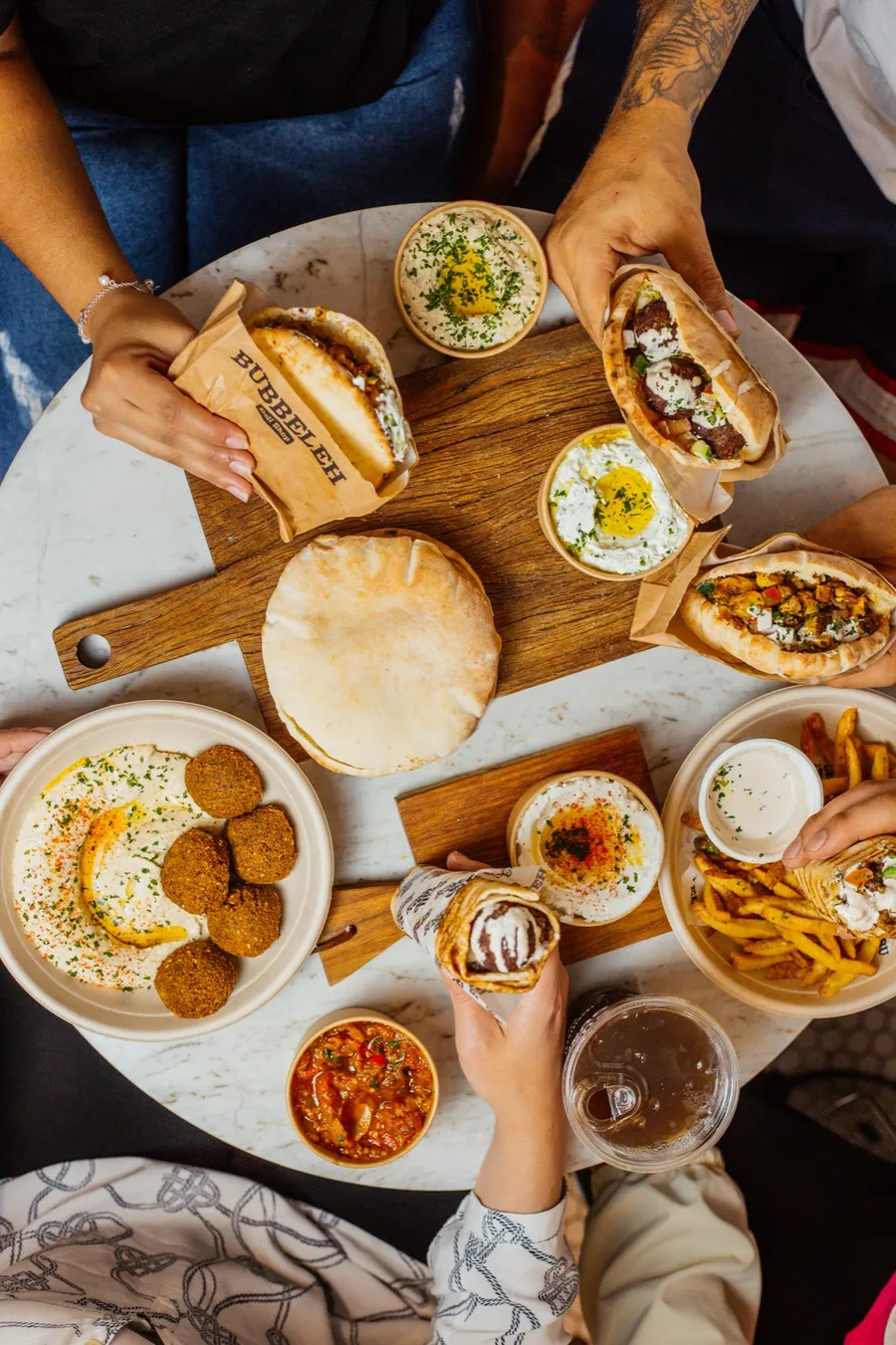 Mesa cheia de pratos do Bubbeleh, compartilhados entre amigos